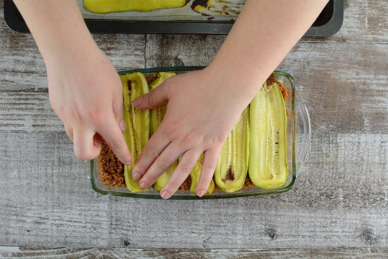 Now, when all the preparations are done, let’s make the layers. On the bottom of casserole dish but spread 1/2 cup of meat sauce. On top of the sauce place your zucchini slices. They can overlap or you can place them side-by-side.